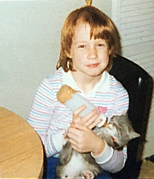 Melissa Moore as a child bottle-feeding a cat